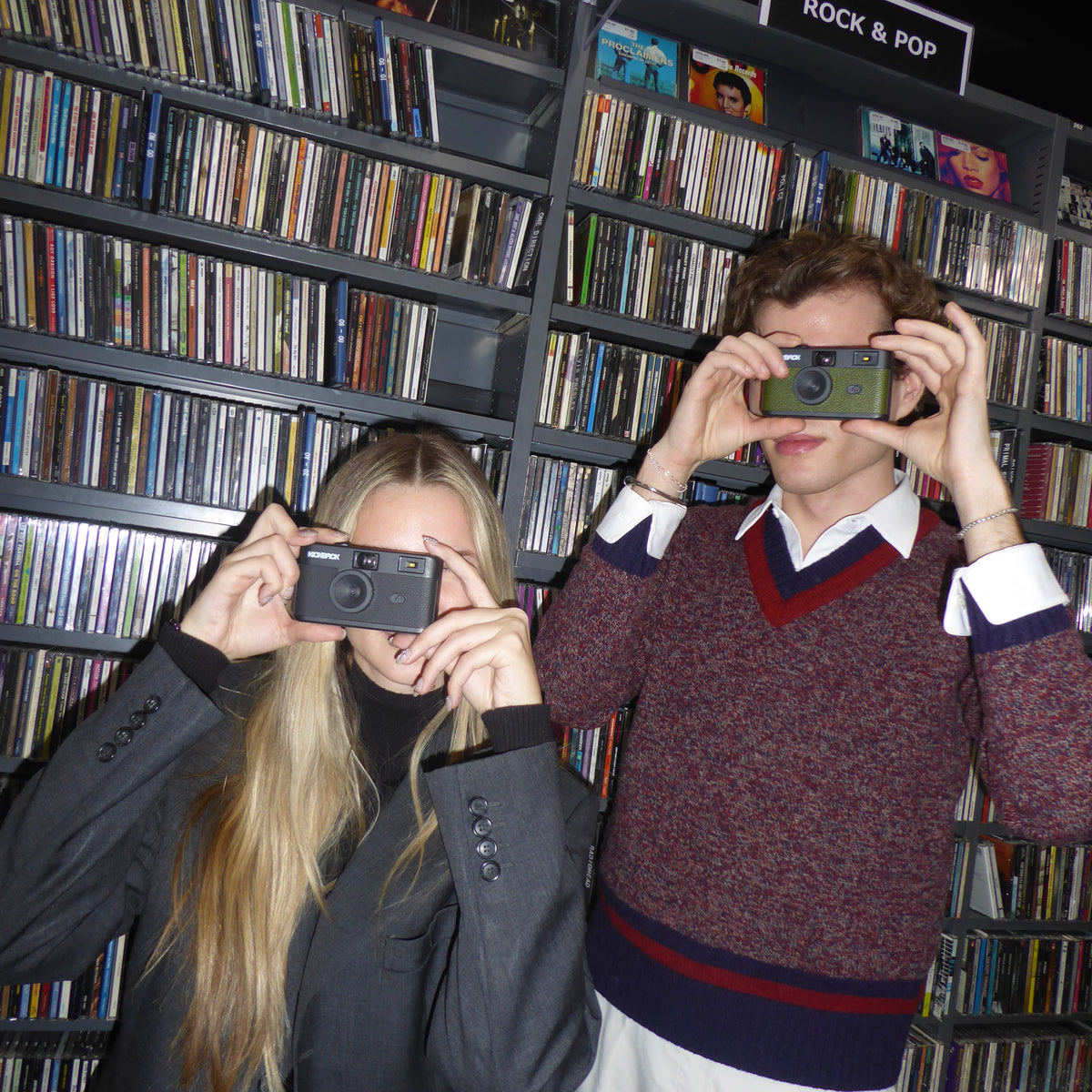 Two people taking a selfie in a record store with vinyl records on shelves.